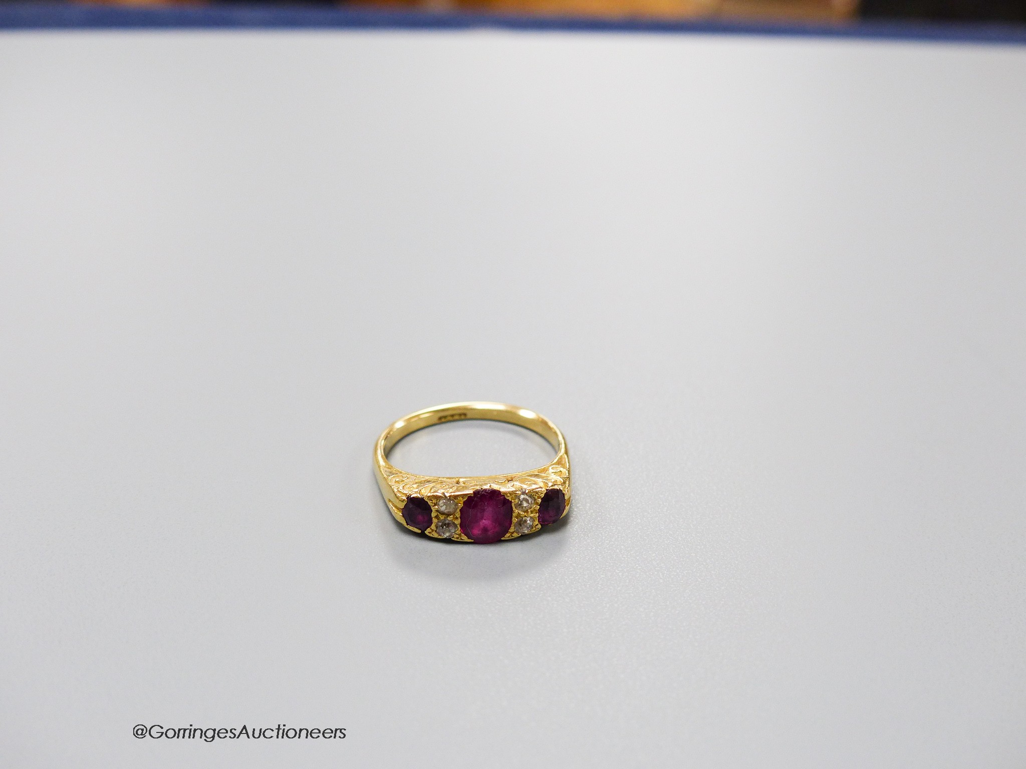 An early 20th century 18ct, three stone ruby and four stone diamond chip set half hoop ring, size L, gross 4.1 grams.